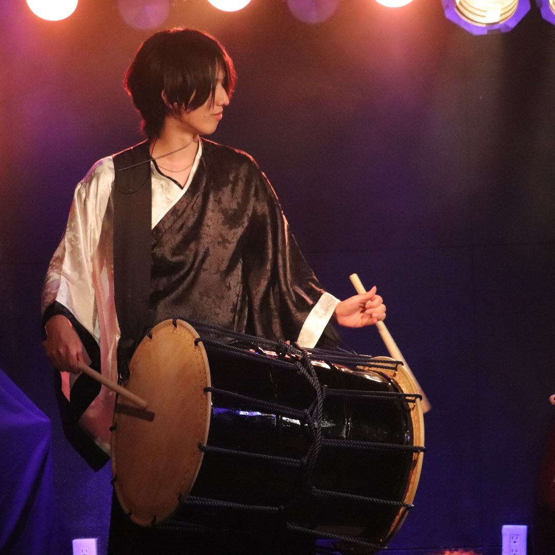 Takuya Sato — playing chu-daiko on stage under warm spotlights
